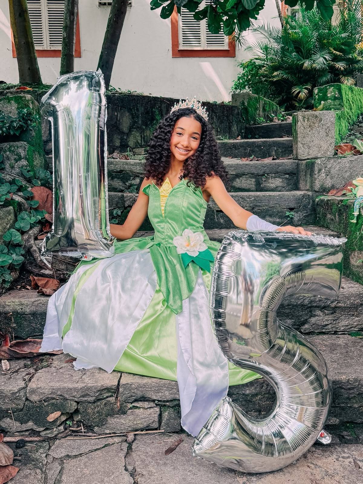 Camille sentada na escadaria com balões de 1 e 5